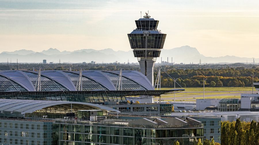 Tower und Terminaldach des Flughafens München vor der Alpenkette.